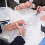 hands of three people, signing documents